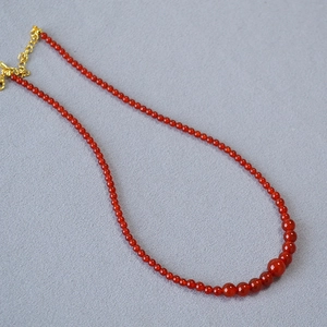 Detailed shot of red agate beaded necklace showing gradient size beads and gold clasp
