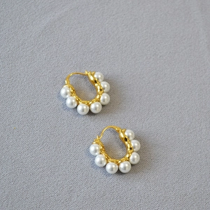 Boucles d'oreilles créoles dorées vintage avec perles baroques sur tissu gris texturé