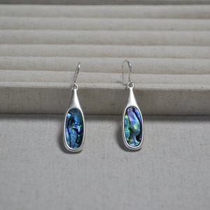 Macro shot of silver teardrop earrings with colorful iridescent abalone shell inlay