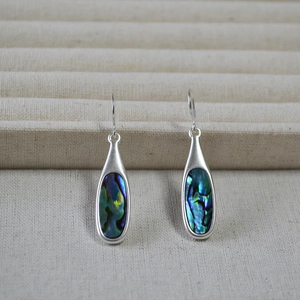 Detailed macro view of silver drop earrings featuring colorful iridescent abalone shell inlay