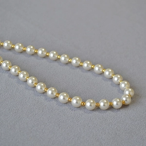 Detailed view of high-luster white pearls with gold bead spacers on a minimalist necklace
