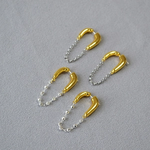 Detailed shot of two-tone U-shaped chain tassel earrings in gold and silver finish