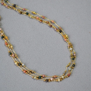 Collier à trois rangs orné de perles de pierres précieuses facettées et métal doré