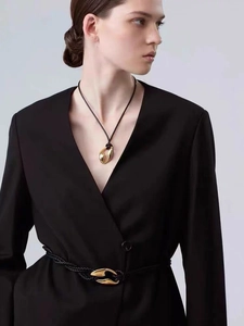 Detail of organic gold-plated pendant with black cord and matching woven leather waist belt