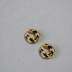 Detail of gold-plated brass hoop earrings featuring black enamel and sparkling zircons