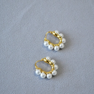 Détail de créoles vintage françaises en métal doré ornées de perles baroques blanches