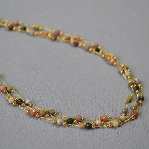 Détail d'un collier à plusieurs rangs avec des chaînes dorées et des perles à facettes