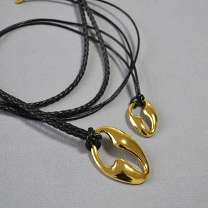 Detail of hollow irregular gold plated brass pendants with black braided cord necklaces