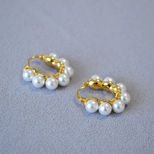 Détail de créoles dorées en C ornées de perles blanches élégantes dans un style vintage français