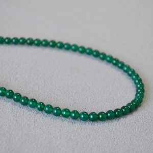 Macro shot of green chalcedony beads showing polished texture and vibrant emerald hue