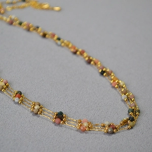 Détail macro du collier multi-rangs avec perles facettées colorées et chaîne dorée