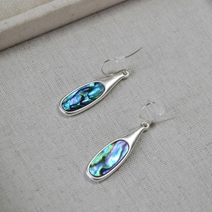 Macro shot of silver teardrop earrings with colorful iridescent abalone shell inlay