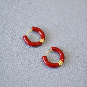 Détail de créoles en émail rouge avec texture en laiton plaqué or et design minimaliste