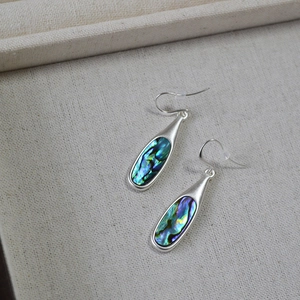 Detailed macro view of silver teardrop earrings with colorful abalone shell inlays