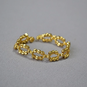 Close-up of gold beaded ring featuring geometric diamond-cut texture and hollow links