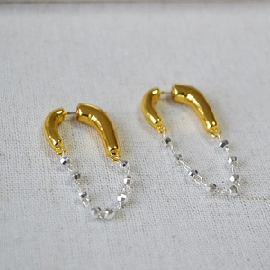 Detailed view of silver and gold chain tassel earrings on a textured fabric background