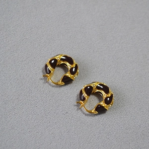 Detailed close-up of vintage gold-plated lava texture earrings with burgundy enamel inlay