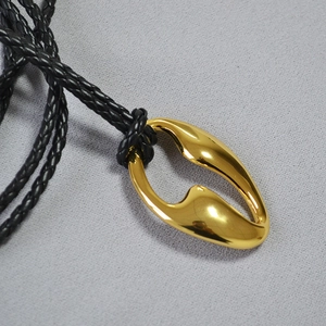 Macro view of gold plated hollow oval pendant with black braided cord necklace