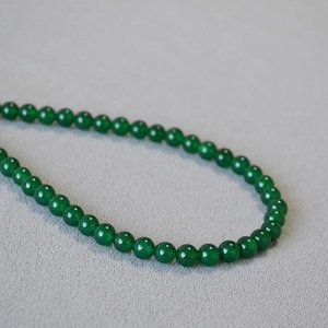 Close-up of translucent green agate beads showing smooth texture and jade-like luster