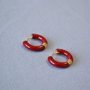 Gros plan de boucles d'oreilles créoles en émail rouge avec fermoir en laiton doré