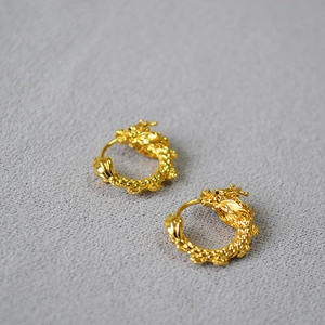 Détail macro de boucles d'oreilles dragon dorées avec textures et écailles fines