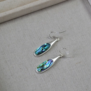 Macro view of vintage silver earrings with inlaid iridescent colorful abalone shell inserts