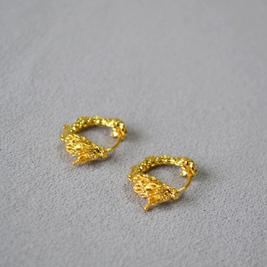 Gros plan détaillé des boucles d'oreilles dragon en laiton doré avec texture métal fondu