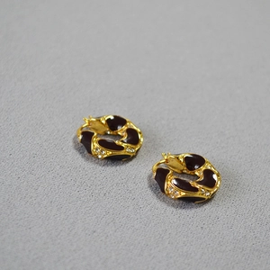 Close-up of vintage gold knotted earrings with black enamel and sparkling white rhinestones