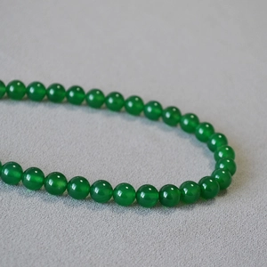 Macro shot of translucent green agate beads showing smooth texture and glossy finish