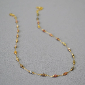 Détail des perles en pierre naturelle facettée et perles dorées sur un collier délicat