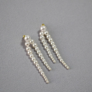 Détail de boucles d'oreilles perles élégantes avec pompons dégradés et accents dorés