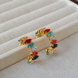 Détail de boucles d'oreilles C dorées ornées de zircons arc-en-ciel taille marquise