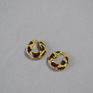 Detail of vintage gold-plated lava texture earrings with burgundy enamel and zircon