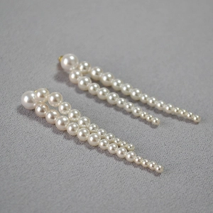 Détail macro de boucles d'oreilles pendantes avec perles blanches et monture dorée