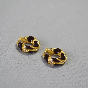 Detail of vintage gold plated earrings featuring lava texture and burgundy enamel inlays