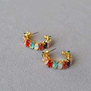 Gros plan de boucles d'oreilles dorées en C avec pierres multicolores marquises
