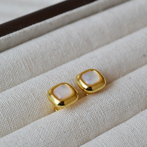 Macro shot of geometric gold square earrings with white mother of pearl inlay