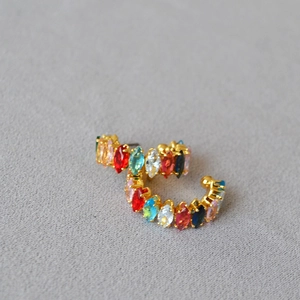 Gros plan sur des boucles d'oreilles C dorées avec des zircons colorés de taille marquise