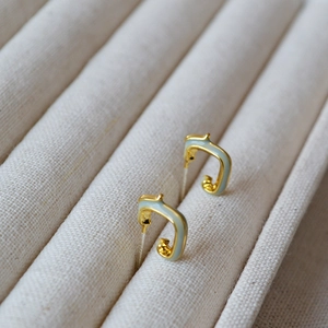 Macro shot of minimalist gold finish dragon hoop earrings with blue enamel detail