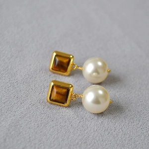 Gros plan de boucles d'oreilles vintage avec œil de tigre et perles blanches polies