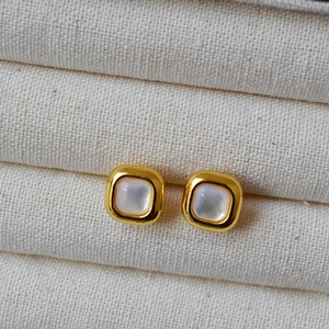 Macro shot of geometric square stud earrings with white mother of pearl inlay and gold finish
