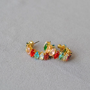 Gros plan de boucles d'oreilles en C dorées serties de zircons marquises colorés