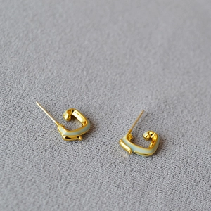 Detail view of handmade enamel blue dragon studs with 925 silver needles on textured fabric