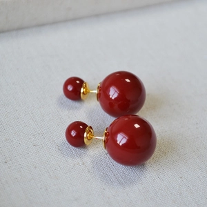Macro detail of elegant burgundy double pearl earrings with gold metallic connection