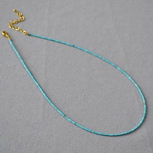 Détail de la chaîne dorée réglable et des perles turquoise pour collier superposé
