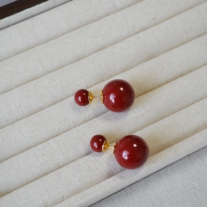 Elegant wine red double pearl earrings with gold stem on a velvet jewelry tray