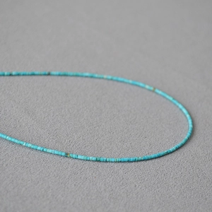 Gros plan d'un collier de perles turquoise avec texture de pierre naturelle mate