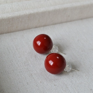 Détail macro de boucles d'oreilles en émail rouge cerise avec tiges en argent 925