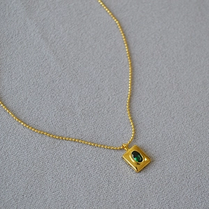 Detail of vintage gold bead chain with rectangular emerald green gemstone pendant