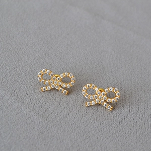 Detail of gold bow earrings featuring a full micro-pave setting with sparkling cubic zirconia